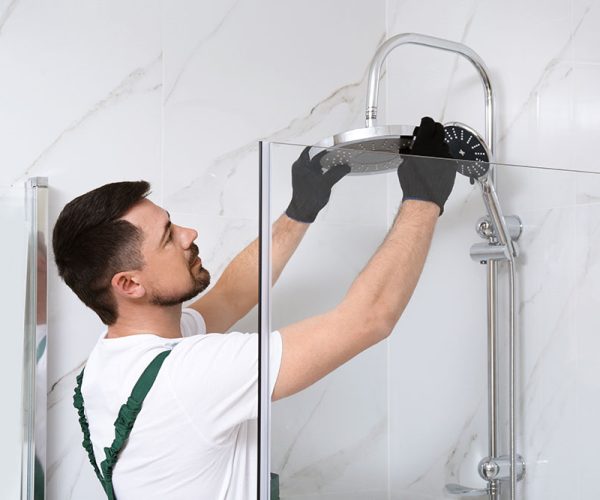 Professional handyman working in shower booth indoors