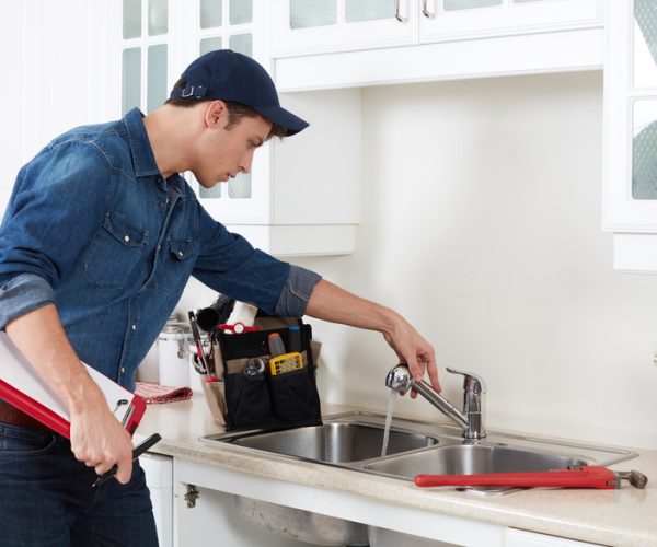 Professional plumber doing reparation in kitchen home.